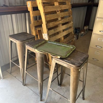 Sale Photo Thumbnail #16: Trio of industrial metal barstools with weathered wooden seats, accompanied by a distressed green painted serving tray.