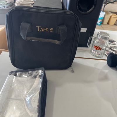 Sale Photo Thumbnail #106: Black Tahoe brand travel accessory bag with a clear organizer pouch, alongside a black audio subwoofer and an Oklahoma State glass mason jar mug.