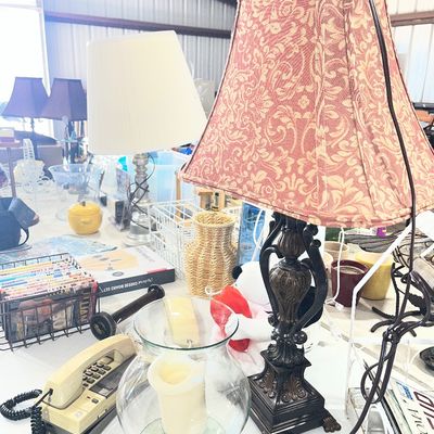 Sale Photo Thumbnail #95: Traditional dark metal table lamp with a patterned fabric shade displayed alongside a vintage push-button telephone, glass hurricane vase, and other household goods.