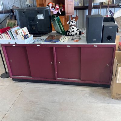 Sale Photo Thumbnail #103: Maroon commercial sliding-door storage Credenza topped with a flat-screen television, books, speakers, and plush toys.