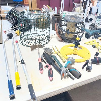 Sale Photo Thumbnail #100: Assortment of garden tools, lawn sprinklers, hose attachments, and bird feeders arranged on a folding table.