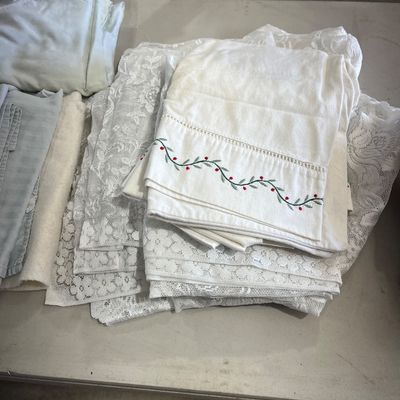 Sale Photo Thumbnail #78: Assortment of vintage linens and textiles, featuring white lace tablecloths and embroidered table runners with vine and berry details.