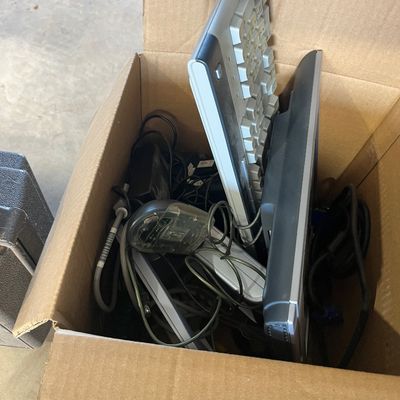 Sale Photo Thumbnail #32: Cardboard box filled with assorted vintage computer peripherals, including keyboards, a mouse, and connecting cables.