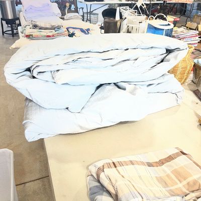 Sale Photo Thumbnail #69: Folded light blue comforter resting on a folding table alongside other linens and household items.