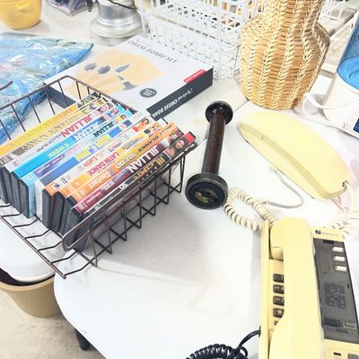 Sale Photo Thumbnail #97: Selection of household goods including vintage corded landline telephones, a wire rack filled with DVDs, a woven vase, and a cheese board set.