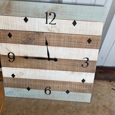 Sale Photo Thumbnail #61: Large rustic wooden wall clock constructed from horizontal slats in white, light blue, and natural wood tones with stenciled black numbers.