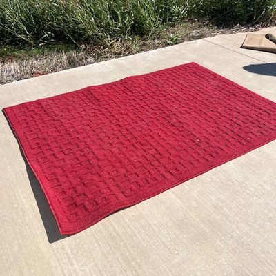 Sale Photo Thumbnail #112: Red rectangular area rug with a geometric, textured low-pile weave, laid out on a concrete surface.