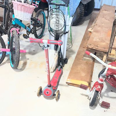 Sale Photo Thumbnail #25: Red Globber three-wheeled kick scooter alongside bicycles, a vintage red tricycle, and badminton rackets in a garage.