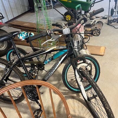 Sale Photo Thumbnail #86: Pair of modern Mongoose mountain bikes stored inside a workshop, including a black Mongoose Montana model with teal wheel accents.