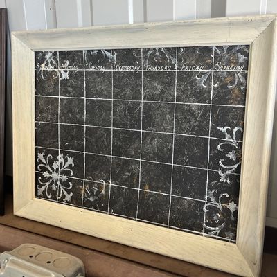 Sale Photo Thumbnail #55: Framed wall calendar featuring a distressed chalkboard-style grid with decorative corner stencils and an off-white wooden frame.