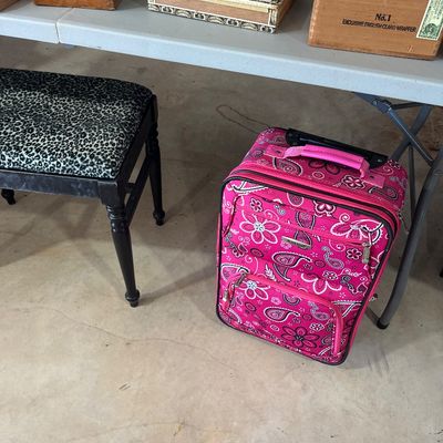 Sale Photo Thumbnail #6: Pink paisley rolling suitcase by Rockland alongside a black vanity stool with leopard print upholstery, with vintage wooden cigar boxes displayed on a table above.