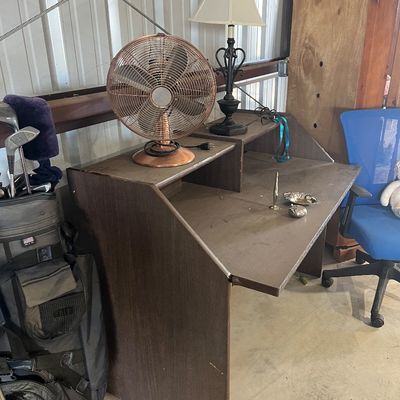 Sale Photo Thumbnail #81: Dark brown laminate writing desk with a upper shelf, displayed alongside a copper-toned electric fan, table lamp, and golf bag.
