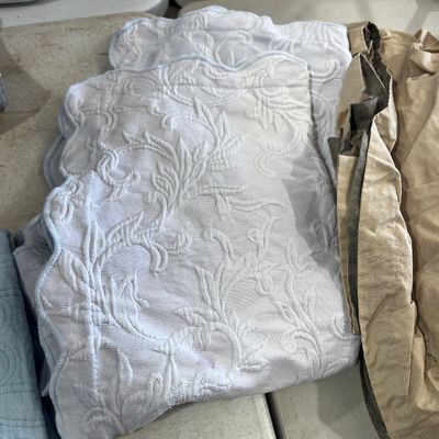 Sale Photo Thumbnail #123: Folded light blue quilted placemats with scalloped edges and a raised floral leaf motif.