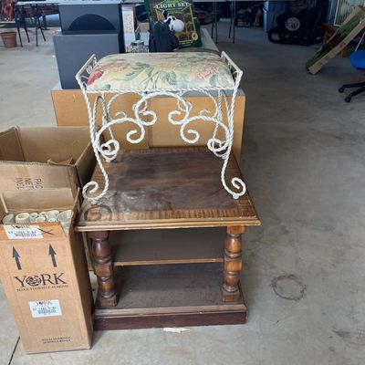 Sale Photo Thumbnail #108: Vintage white wrought-iron vanity stool with a floral fabric cushion, sitting atop a dark wood end table with turned legs.