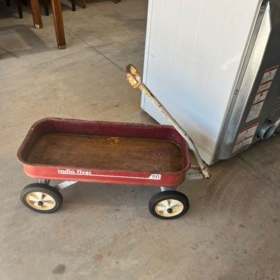 Sale Photo Thumbnail #110: Vintage red Radio Flyer 9A toy wagon showing surface rust and wear on the bed and handle.