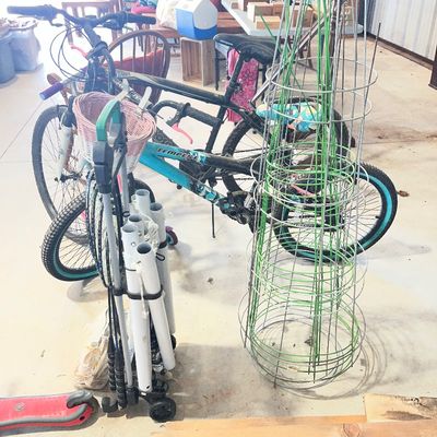 Sale Photo Thumbnail #11: Collection of outdoor and sporting goods including a blue Mongoose Tempest bicycle, a black mountain bike, tomato cages, and a portable volleyball or badminton net set.