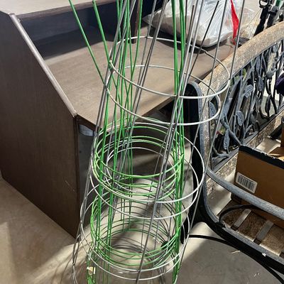 Sale Photo Thumbnail #133: A stack of metal and green coated wire tomato cages for garden use.
