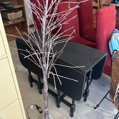 Sale Photo Thumbnail #15: Artificial lighted frosted birch tree decor piece, standing in front of a dark painted drop-leaf dining table.