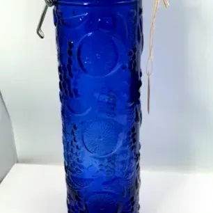 Tall cobalt blue glass spaghetti jar with a wire bale lock lid and embossed fruit motifs.