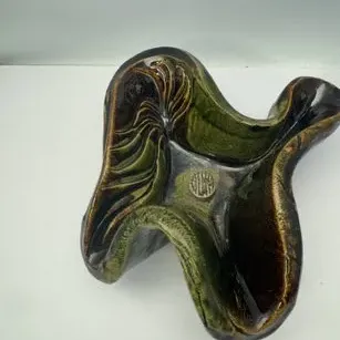 Vintage mid-century art pottery bowl with an organic, wavy form in green and dark brown glazes.