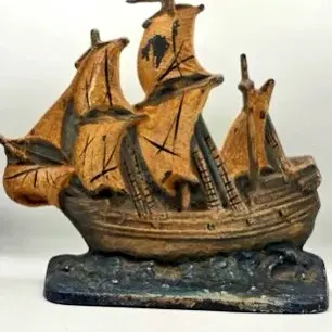 Vintage painted cast iron nautical ship doorstop featuring a three-masted sailing vessel on a wave base with original distressed finish.