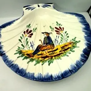 French Quimper style hand-painted ceramic shell dish featuring a traditional Breton figure and floral motifs.