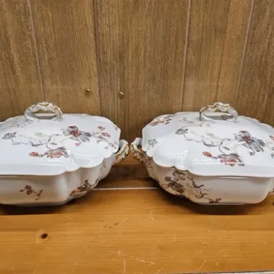 Pair of vintage porcelain covered vegetable tureens featuring delicate floral patterns and gilt accents.