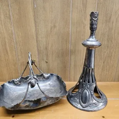 Pair of ornate silverplate tabletop items, including a handle-equipped bride's basket dish and a tall decorative candlestick stand,...