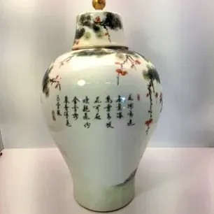 Chinese porcelain ginger jar featuring hand-painted floral and pine branches, calligraphy inscriptions, and a gold-toned finial lid.