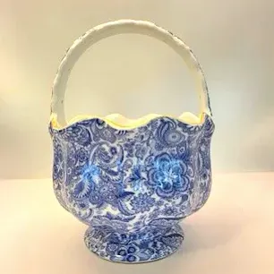 Blue and white calico floral ceramic basket with handle and scalloped rim.