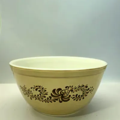 Vintage Pyrex Homestead pattern yellow mixing bowl featuring a dark brown floral scroll print.