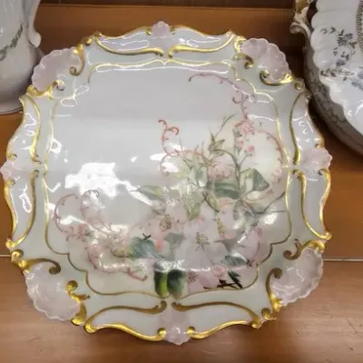 Antique hand-painted porcelain cabinet plate featuring delicate pink floral motifs, scrollwork accents, and ornate gilded Rococo-style...