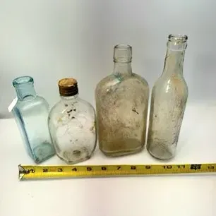 Collection of four antique glass bottles, including an aqua-tinted apothecary bottle, in varied shapes and sizes.