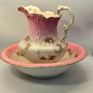 Antique Victorian wash basin and pitcher set with pink gradient accents, molded scrolled details, and floral transferware design.