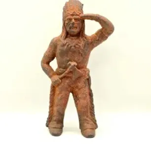 Vintage cast iron Native American chief doorstop or figurine with a heavily rusted finish, depicting a scout holding a tomahawk.