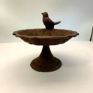 Cast iron bird bath or feeder bowl featuring a scalloped edge and a small perched bird figurine on the rim.