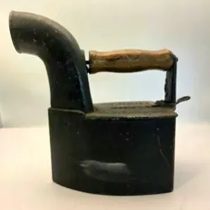 Antique cast iron charcoal iron with wooden handle and smoke spout, showing minor surface wear and patina.