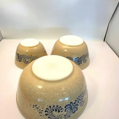 Set of three vintage Pyrex Homestead pattern nesting mixing bowls, displayed upside down to show the speckled beige exterior and blue...