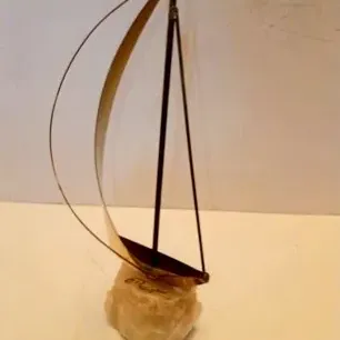 Vintage brass sailboat sculpture mounted on a rough-cut quartz or alabaster stone base.