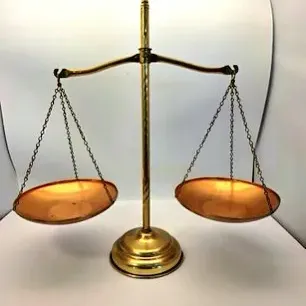 Vintage brass balance scale with suspended copper-toned pans.