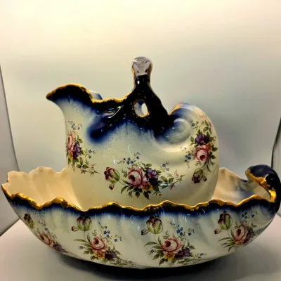 Antique porcelain wash basin and pitcher set featuring hand-painted floral motifs, cobalt blue accents, and gilded trim.