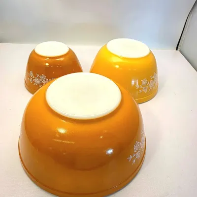 Set of three vintage Pyrex mixing bowls in the Butterfly Gold pattern, resting upside down.