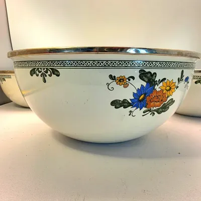 Vintage white enamelware mixing bowl featuring a stainless steel rim and colorful floral decal pattern.