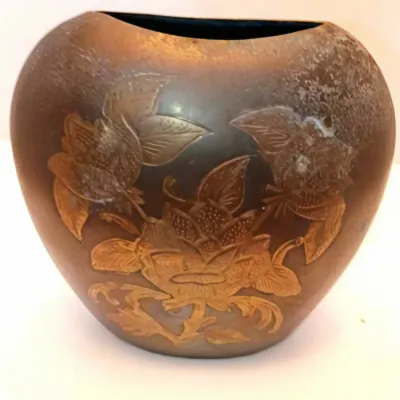 Vintage dark bronze or copper vessel featuring relief-carved or etched floral and butterfly motifs, showing age-related patina and finish...