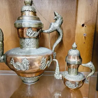 Pair of ornate Tibetan or Himalayan copper and brass teapots, featuring embossed dragon motifs and dragon-shaped handles and spouts.