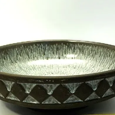 Mid-century studio pottery ceramic bowl featuring a speckled light blue interior glaze and a raised geometric diamond pattern on the dark...