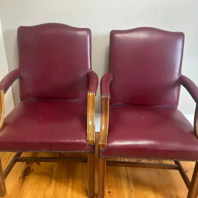 Matching wood-framed guest/office chairs with burgundy leather upholstery and brass nailhead trim.