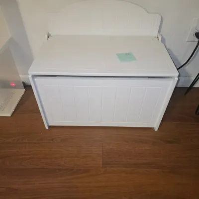 Sale Photo Thumbnail #36: White painted wooden toy box / storage bench featuring beadboard-style front panel detail, side handles, and a safety hinge soft-close lid mechanism. Appears in good pre-owned condition with light cosmetic wear consistent with use.