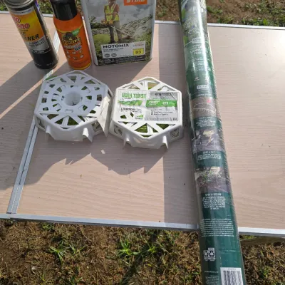 Sale Photo Thumbnail #176: Assortment of lawn and garden maintenance supplies including a roll of landscape fabric (3 ft x 100 ft), two spools of Ugly Twist commercial grade trimmer line (.080 in / 320 ft), a metal can of Stihl MotoMix premixed fuel, a can of Gorilla Spray Adhesive