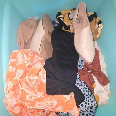 Sale Photo Thumbnail #134: An assortment of women's apparel and footwear stored inside a light blue plastic storage tub. Includes distressed blue jeans (brand: Cello, some items retaining original retail tags), pattern tops, animal prints, casual wear, and a pair of nude flat shoes